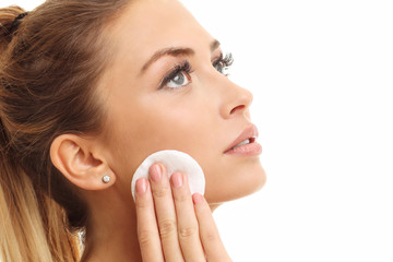Portrait of adult woman smiling and using cotton pad against white background © Kalim