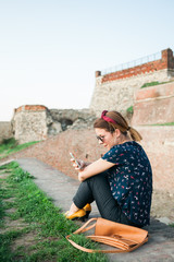 Fototapeta premium Young woman sitting in the park using smartphone