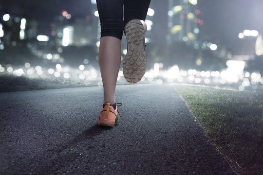 Frau joggt bei Dunkelheit in einem Park