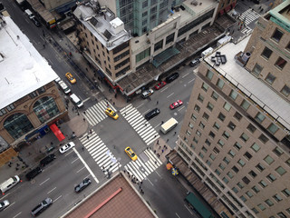 Bird's eye view of 5th Avenue from tall New York City skyscraper.  Busy Manhattan intersection.  New York yellow taxis and people crossing busy city intersection.  Urban New York life. Looking down.