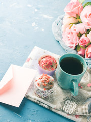 Mother's day Valentine concept muffins with hearts sprinkles and cup of tea on napkin. Flowers