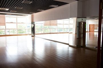 Empty dancing room with hardwood floor and mirror.