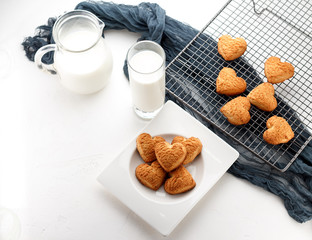 Cookies. freshly baked heart homemade biscuits with a cup of milk over white background.
