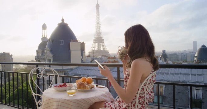 Travel woman using smartphone at Eiffel Tower Paris sharing social media view from hotel terrace breakfast vacation