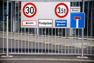 Schilder am Eisentor / Viele verschiedene Verkehrsschilder an dem eisernen Eingangstor eines Industriegel&auml;ndes.