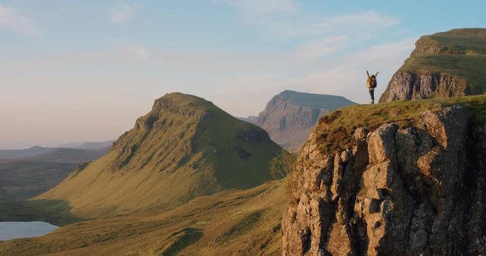 Woman with arms raised on top of mountain looking at Sunrise view Hiker Girl celebrating scenic landscape enjoying nature vacation travel adventure Quiraing Walk on the Isle of Skye in Scotland