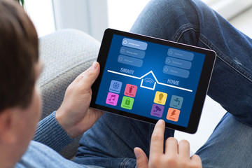 man in jeans holding tablet with app smart home screen