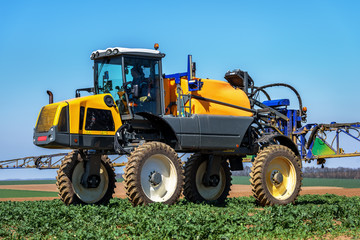 Obraz na płótnie Canvas Farm machinery spraying insecticide to the green field.