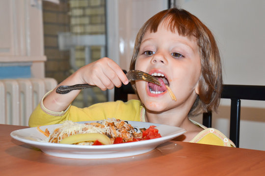 Cute little brown hair girl eating spaghetti 