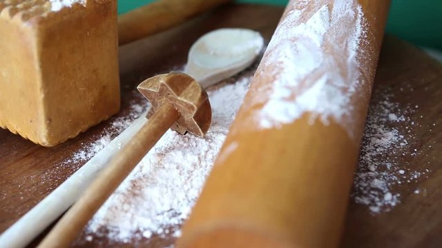 rotating wooden board with cooking spoon and pastry roller and flour
