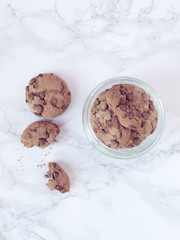 Crisp chocolate cookies in a jar on marble background. Flat lay. Top view