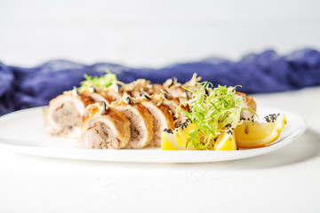 Baked chicken roll with mushrooms and slices of lemon. White background. The concept of nourishing food.