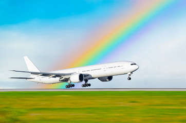 Fototapeta na wymiar The airplane on the background of the rainbow landed at the airport