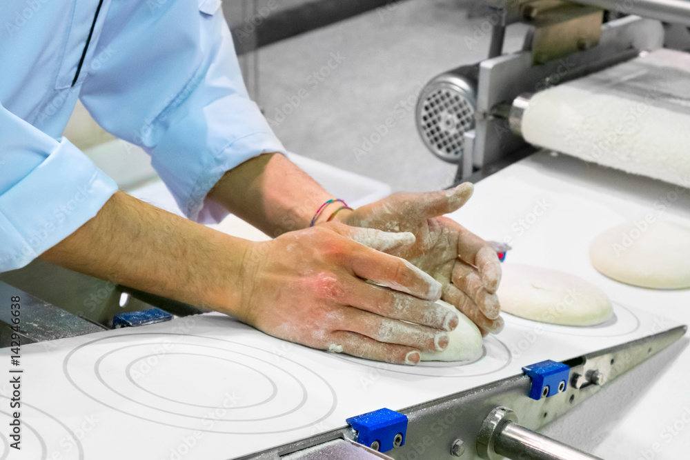 Poster close-up the hand of a baker kneading and shaping a dough. private bakery. production of bread.