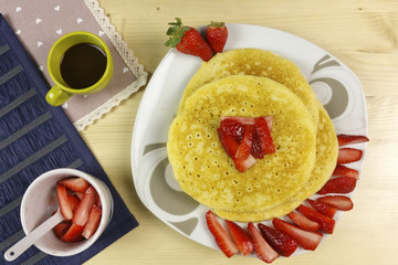Pancakes and strawberries on wood background - top view