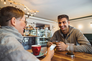 Couple young guy and girl talking in a cafe. A break for young entrepreneurs over a cup of coffee in a stylish cafe interior.