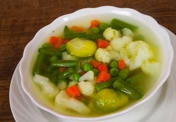 Fresh vegetable soup in bowl on wooden table