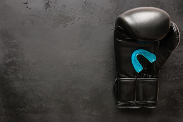 One boxing glove and a mouth guard on a black background with space for text