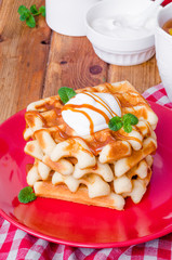 Stack Belgian waffles with caramel sauce and whipped cream on a plate.
