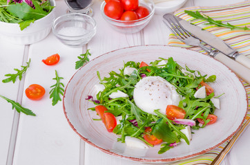 Fresh salad with arugula, mozzarella, cherry tomatoes and poached egg