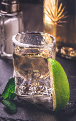 Shot glass of tequila gold and lime. Toned