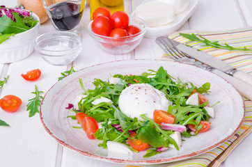 Fresh salad with arugula, mozzarella, cherry tomatoes and poached egg