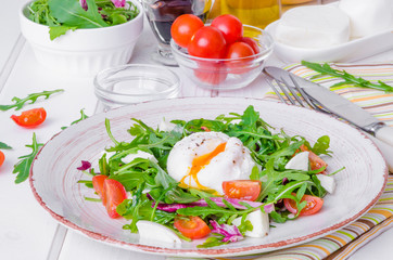 Fresh salad with arugula, mozzarella, cherry tomatoes and poached egg