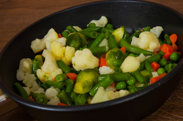 Mixed vegetables in a frying pan. on wood table