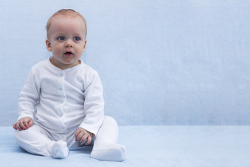 Calm little baby boy sitting in Buddha posture. Tranquil infant kid looking at camera. Copy space