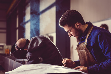 Industrial Welder checking blueprint