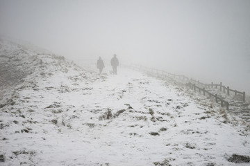 Beautiful Winter landscape image around Mam Tor countryside in Peak District England with hikers in fog