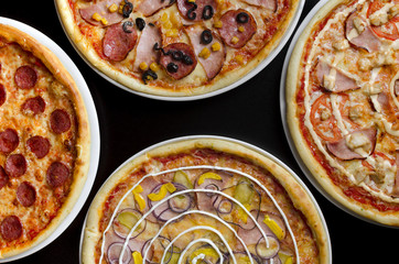 Four different pizzas on a white plate and a black table