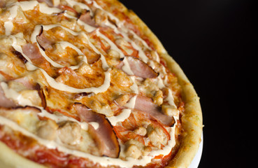 Pizza with chicken and vegetables on a white plate and a black table