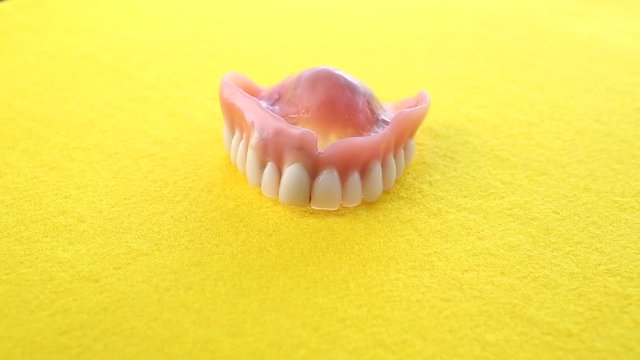 closeup of teeth denture on rotating yellow plate
