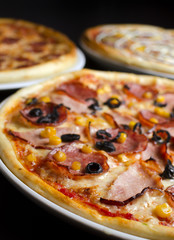 Three different pizzas on a white plate and a black table