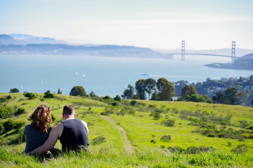 Fototapeta na wymiar Couple Overlooks Golden Gate Bridge Sunny Day
