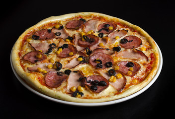 Pizza with ham and olives on a white plate