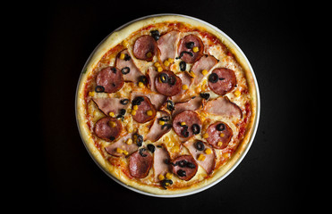 Pizza with ham and olives on a white plate