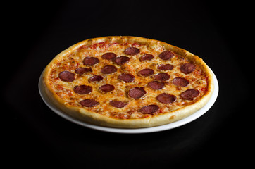 Pizza with salami on a white plate