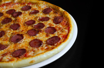 Pizza with salami on a white plate