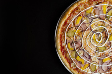 Pizza with pickled cucumbers and ham with sauce on a white plate