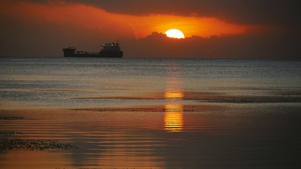 Ship at sunset. The sun sets over the sea at the Fishing Base in Garapan, Saipan. 