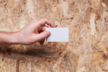 Man's hand is holding a business card on wooden background