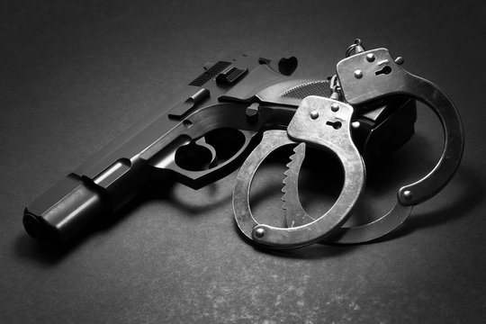 handgun with handcuffs on dark background, law enforcement, crime concept