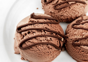 close-up brown ice cream scoops with chocolate sauce on plate