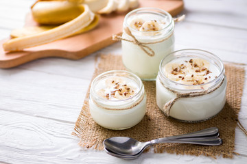 Yogurt in glass jars on wooden background