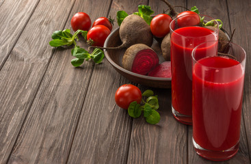 Healthy eating, dieting and vegetarian concept - glass juges of beet-tomato juice with vegetables on dark wooden background . Detox and healthy diet . Copy space.