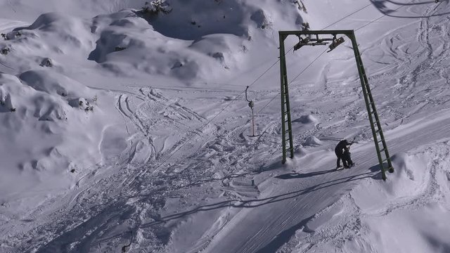 Unrecognizable skiers using t-bar ski lift up the slope on European Alps