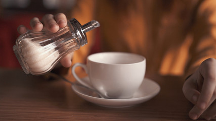 white cup and sugar bowl in hand