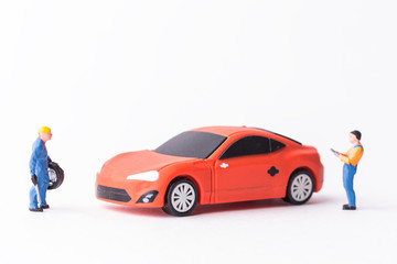 The concept of the workshop tire fitting. Miniature mechanics repairing toy car wheel, close up.